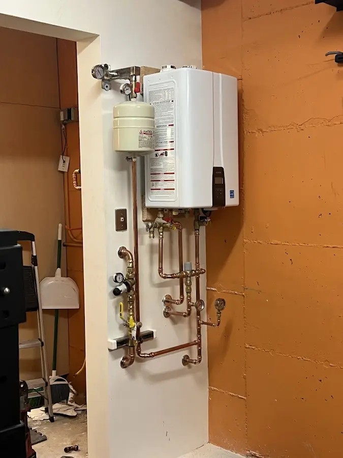 Plumbing technician inspecting water heater connections in North Liberty